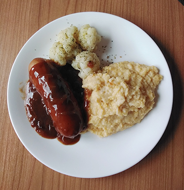 Gebratener Cervalat an einer Zwiebelsauce mit Polenta und Blumenkohl
